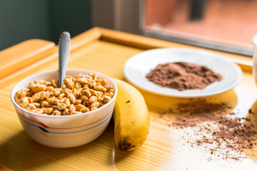 Breakfast with cereals in a bowl with milk, cocoa and banana