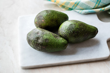 Organic Whole Ripe Avocado on Marble Board.