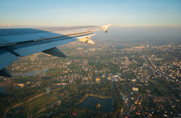 View from wing planes Flying through the city at sunset while travelling to the destination,Transportation and travel concept.