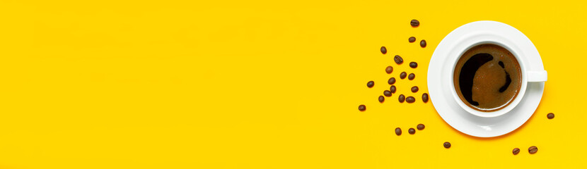 Flat lay cup of black coffee and coffee beans on yellow background top view copy space. Minimalistic food concept, morning breakfast, time to work, hot drink, coffee background