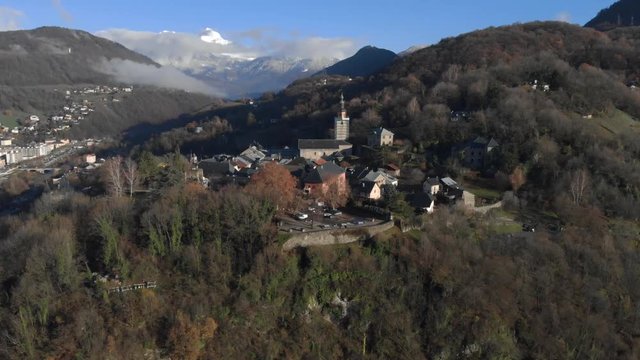 Drone shot over looking the medieval city of Conflans, in the French Alps , focus on the church of the village, in the middle of the mountains, on a sunny day. Drone is going forward