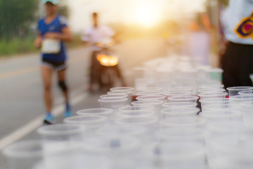 Runner take a water in a marathon race with sunrise