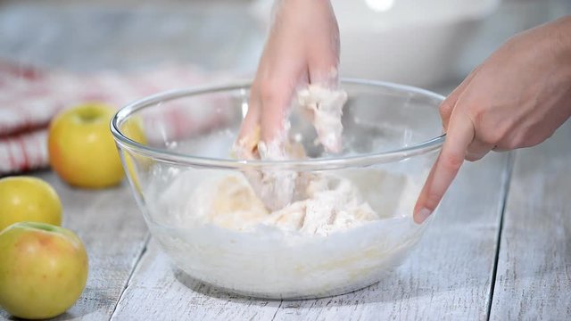Baker hands kneading dough in flour in a glass bowl. Making sweet buns.