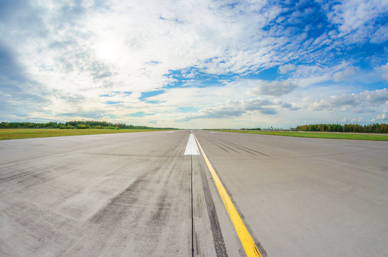 Runway clear for take off, airstrip with marking on blue sky with clouds background. Travel aviation concept