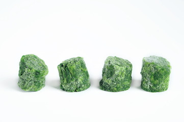 Frozen spinach on a white background. Spinach has the shape of cylindrical bars. Bars are displayed...
