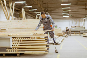 Disabled young man with an artificial leg is working at furniture factory - obrazy, fototapety, plakaty