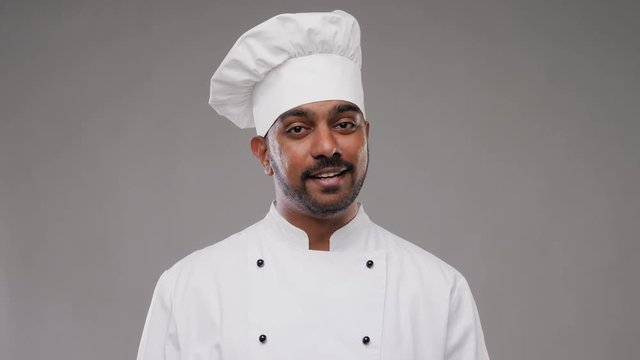 cooking, profession and people concept - happy male indian chef in toque talking over grey background