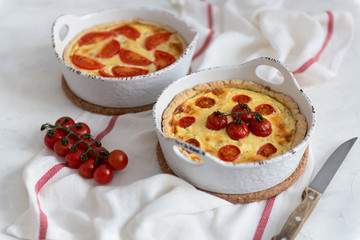 Tomato pies on white tablecloth. Homemade french quiche with cherry tomatoes, copy space