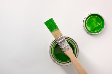 Paintbrush on green paint pot on white table top view