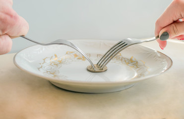 They are trying to divide the  coin on a plate by forks