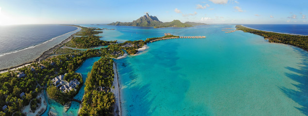 Aerial panoramic landscape view of the island of Bora Bora in French Polynesia with the Mont Otemanu mountain surrounded by a turquoise lagoon, motu atolls, re - obrazy, fototapety, plakaty