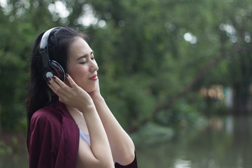 Young beautiful woman running in autumn park and listening to music with headphones.