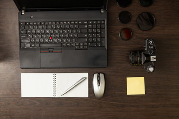 Workspace of professional photographer. Photography and office equipment on the dark desktop.