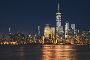 New York City business district skyline at night, color toning applied, USA.
