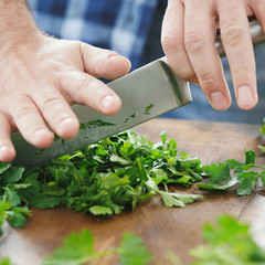 Close up male hands chopped parsley wooden table