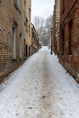 Fototapeta na wymiar Riga. Latvia. Winter landscape with pedestrian path between old brick houses.