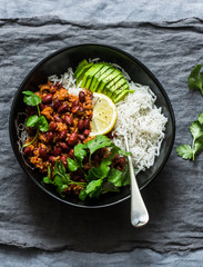 Rice bowl with spicy beans minced meat stew with cilantro and avocado on grey background, top view