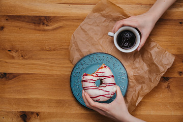 Top-shot of a woman eating doughnut and drinking coffee