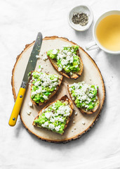 Avocado, goat cheese, grilled ciabatta sandwiches and green tea on light background, top view. Healthy breakfast or snack