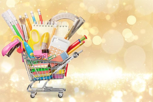 Stationery objects in mini supermarket cart on  background
