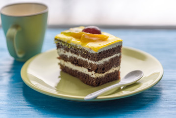 Biscuit cake with fruit tops photographed close-up on wooden background.