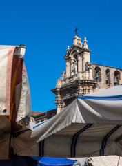 Sanctuary of the Madonna del Carmine in Catania towering over old umbrellas of local food market