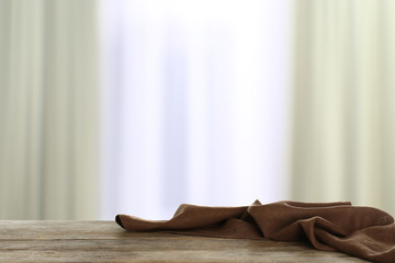 Crumpled napkin on wooden table in room against blurred background. Space for design