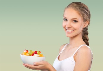 Young woman eating delicious food with fork on green background