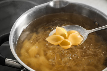Cooking pasta in pot on stove, closeup view