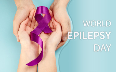 International or world Epilepsy Day concept. The text and a purple ribbon with female hands on a...