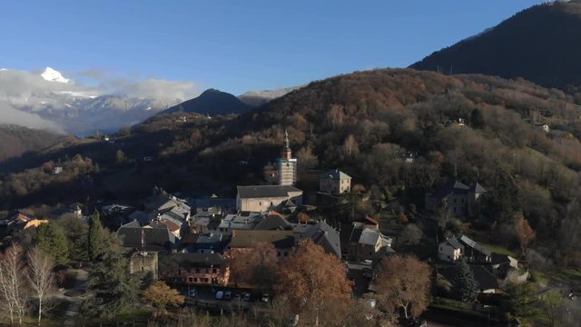 Drone shot over looking the medieval city of Conflans, in the French Alps , focus on the church of the village, in the middle of the mountains, on a sunny day. Drone is turning around the church.