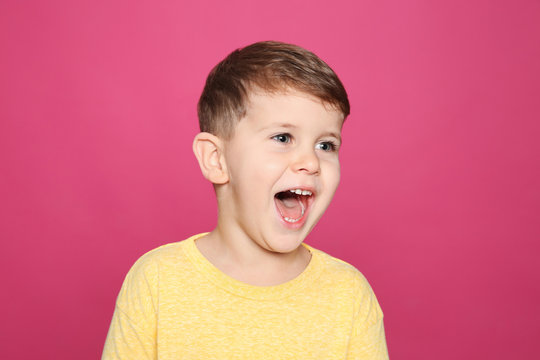 Portrait of little boy laughing on color background