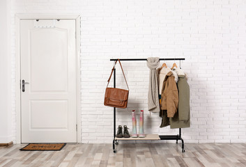 Stylish hallway interior with shoes and clothes on hanger stand