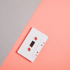 White audio cassette on a pale gray-pink background