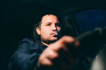 driving with a cigarette in hand, a man Smoking behind the wheel