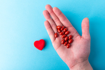 Pills from jar and red heart on blue background. Heart tablets. Coenzyme q10.