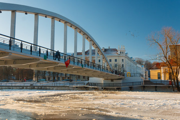 Pedestrian bridge Kaarsild and the view on the embankment of Emajõgi river during winter in Tartu, Estonia