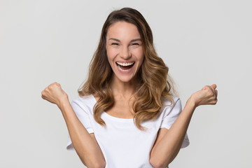 Happy young woman celebrating win looking at camera screaming with joy isolated on white studio...