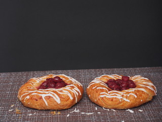 Two sweet cheesecakes with cherries are on the tablecloth.