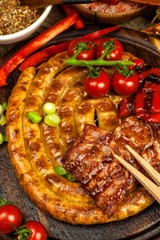 Grilled sausages spiral served on rustic round cutting board with mustard. Homemade barbecue. Garden party. Food preparation.