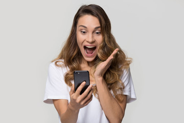 Excited young woman amazed by unbelievable shopping mobile app sale message looking at smartphone,...