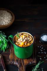 Soup in vintage metal mug on old wooden background.