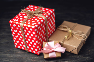 Holiday gift boxes Packed in crafting paper and red polka dots on dark wooden background. Concept of cards with gifts