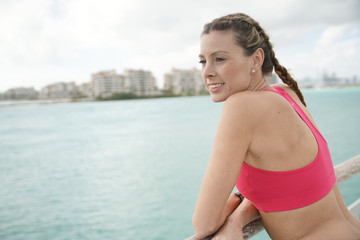 Fototapeta na wymiar Attractive woman in sportswear thinking by waterfront after run