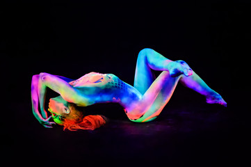 Female dancer in bright neon colours under ultraviolet light on background.