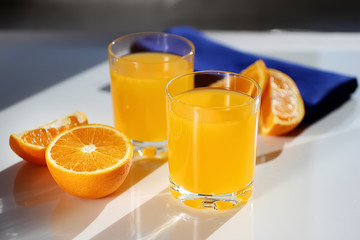 Freshly squeezed orange juice in glass cups, blue napkin and fresh oranges.