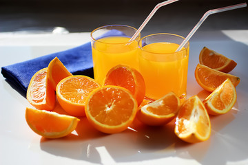 Freshly squeezed orange juice in glass cups, blue napkin and fresh oranges.