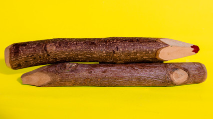 Traditional wooden handicraft big pencils sides isolated in saturated yellow background 
