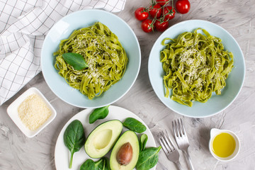 Cooked green spinach tagliatelle pasta on a plate with Parmesan cheese and avocado sauce, Italy...