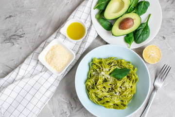 Cooked green spinach tagliatelle pasta on a plate with Parmesan cheese and avocado sauce, Italy food, healthy concept, vegetarian